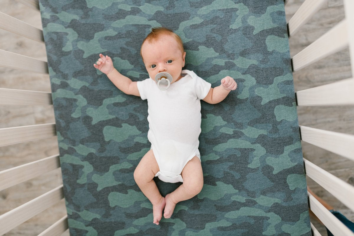 Copper Pearl Premium Knit Fitted Crib Sheet in Hunter color, showing soft, snug fit on a crib mattress with a textured knit fabric.