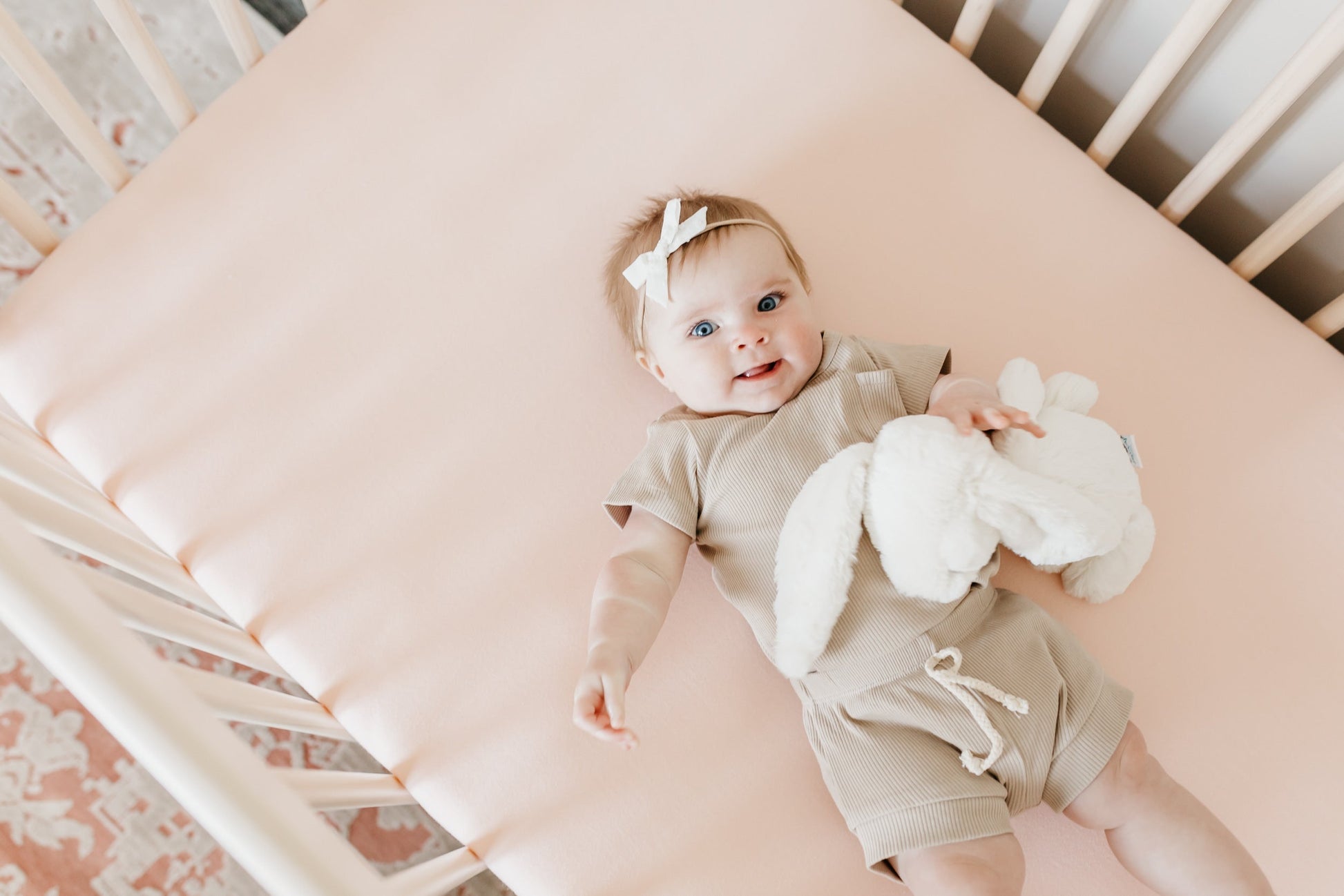 Copper Pearl premium knit fitted crib sheet in blush color, soft and snug for a cozy baby crib.